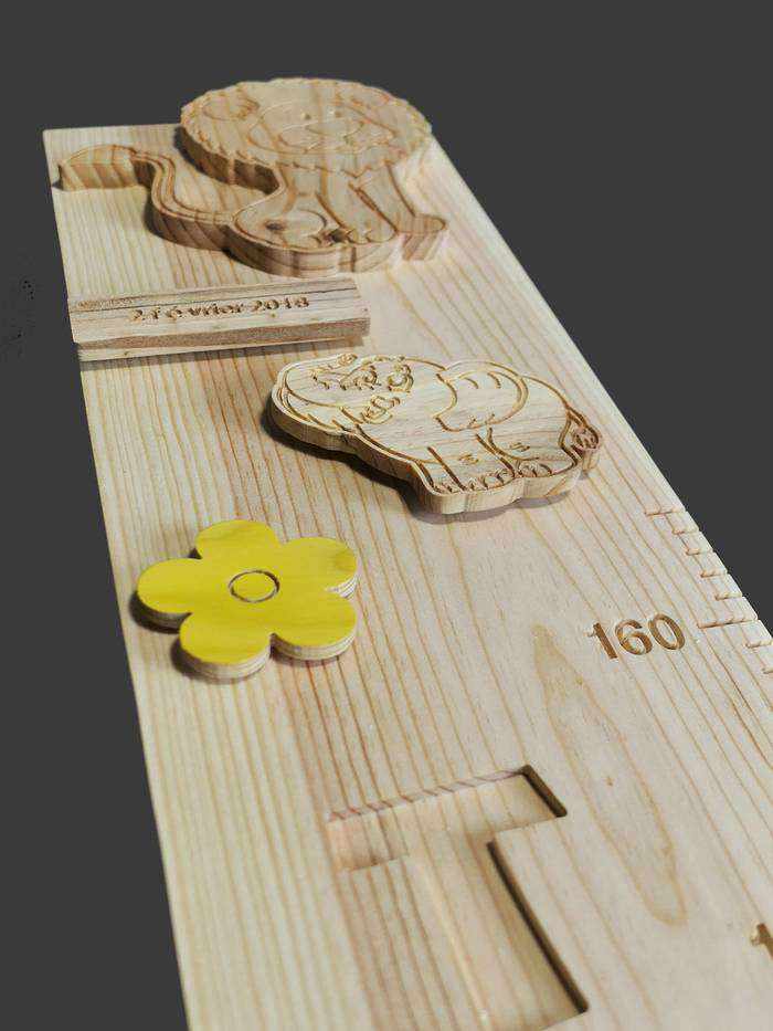 Haut d'une très jolie toise en bois sur-mesure sur le thème de l'Afrique, avec un lion sculpté et des figurines d'éléphant.