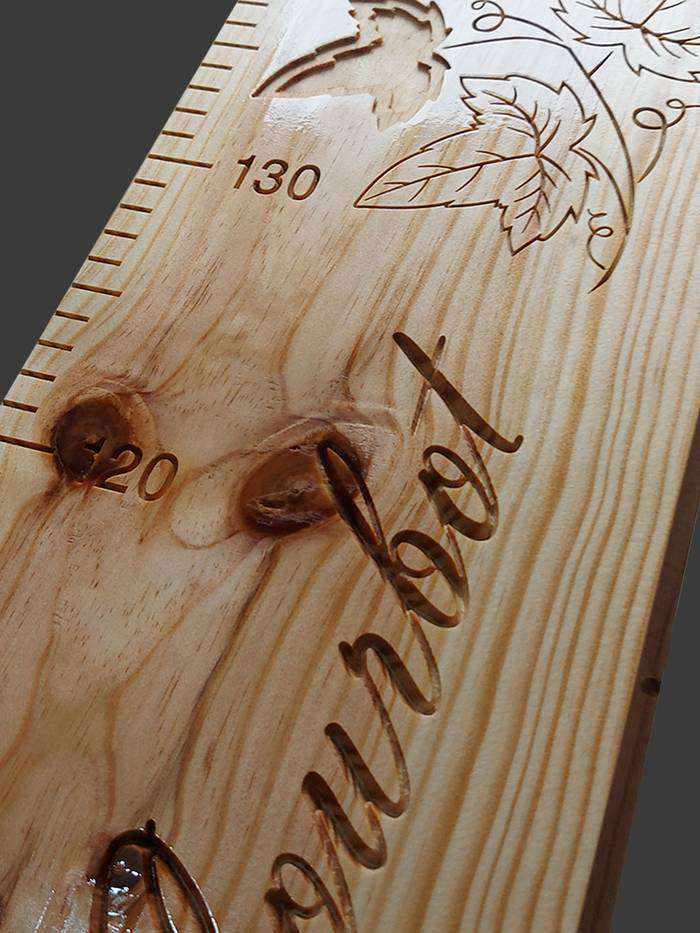 Toise en bois familiale avec le nom sculpté en cursive, accompagné de feuilles de lierre travaillées de différentes façons.
