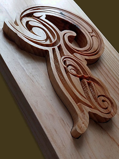 Première lettre du nom de famille sculptée en haut de la toise, dans un style celtique avec des arabesques.