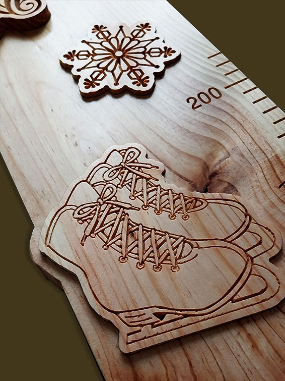 Détail des patins à glace et étoile de neige sculptés dans la toise en bois, symboles du patinage artistique.