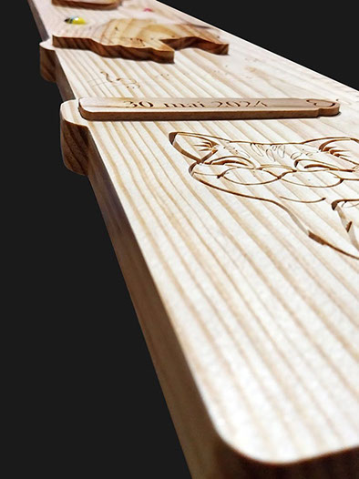 Détail de la toise avec le prénom en écriture cursive incrusté et un nœud naturel bien visible dans le bois.