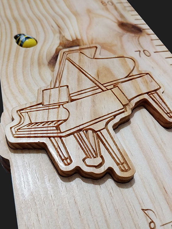 Détail de la toise avec le prénom en écriture cursive incrusté et un nœud naturel bien visible dans le bois.