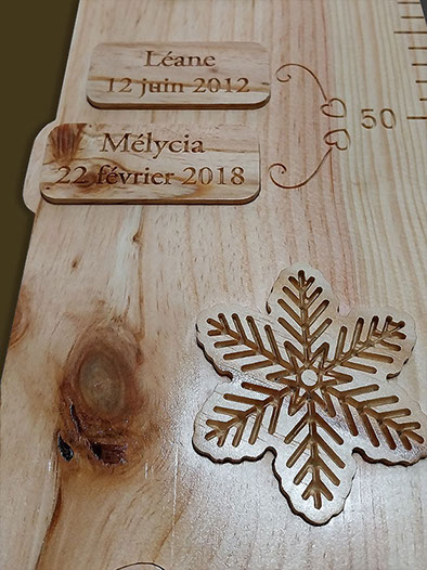 Plaquettes incrustées dans la toise avec les prénoms et dates de naissance des sœurs, à hauteur de leur taille de naissance.