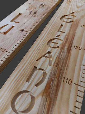 Deux toises côte à côte, montrant de magnifiques veines du bois, avec des prénoms sculptés en élégante écriture celtique.