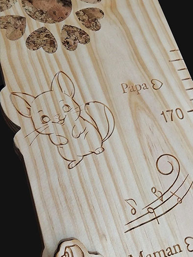 Détail de la toise avec le prénom en écriture cursive incrusté et un nœud naturel bien visible dans le bois.