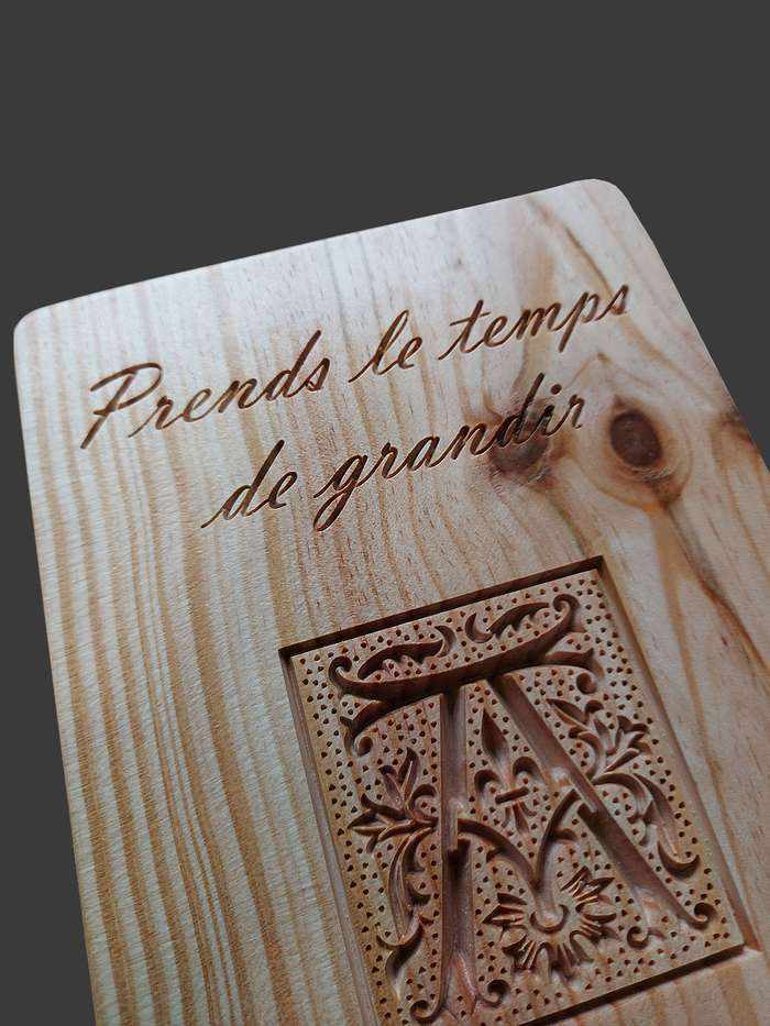 Haut de toise avec une initiale celtique en lettrine, la phrase sculptée 'prends le temps de grandir' et des détails fins.