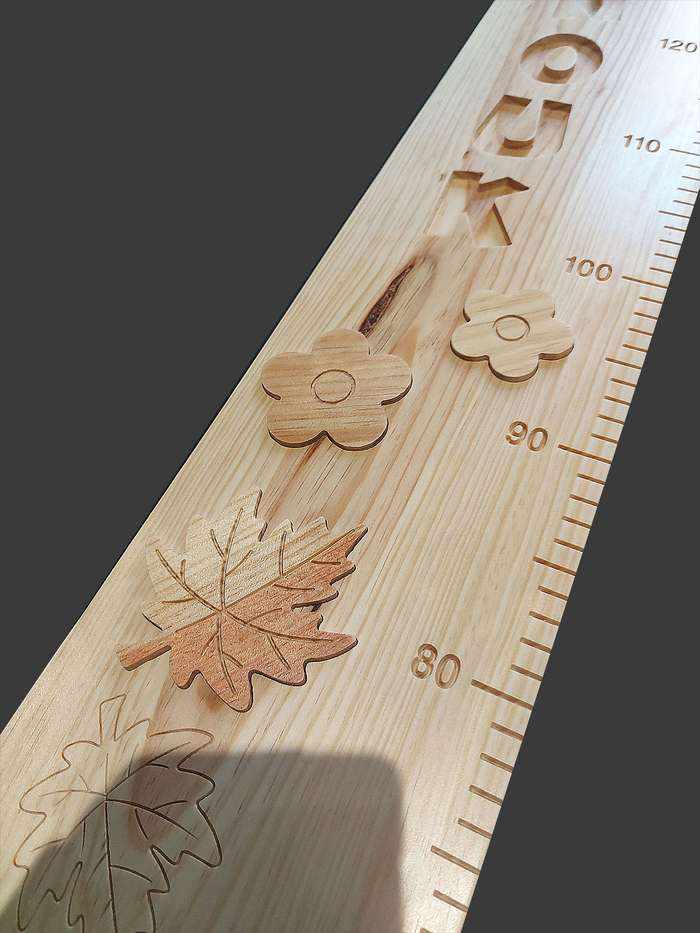 Grande partie d'une toise avec des feuilles d'érable en bois insérées, et des graduations précises au millimètre près.