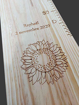 Gros plan sur la fleur de tournesol sculptée dans la toise en bois. Tout y est, multitude de pétales et pistil de la fleur.